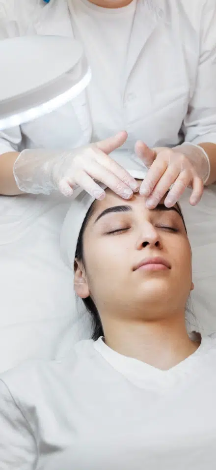 Woman laying on a bed receiving a skin treatment.