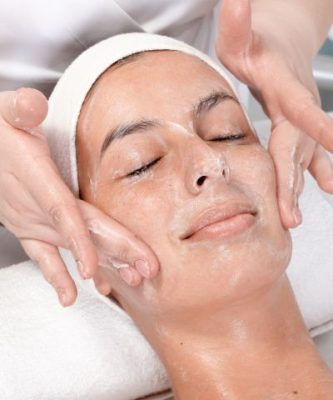 A woman receives a face scrub facial