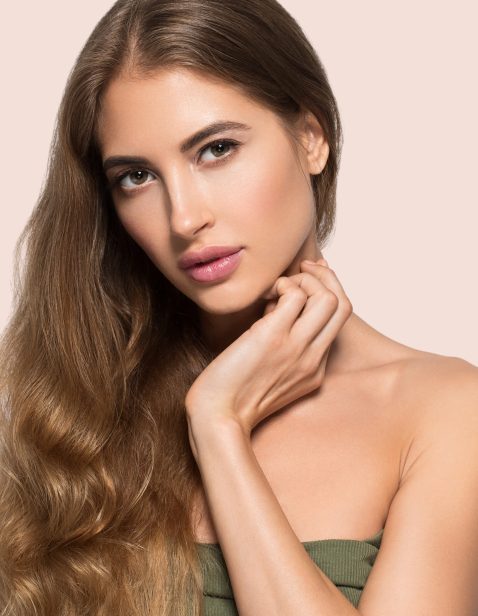 Woman beautiful face healthy. Beauty young model touching herself. Color background. Pink